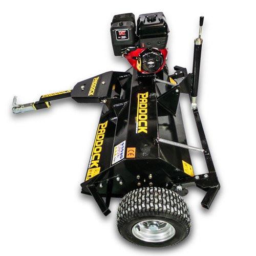 Black tow-behind slasher mower with large wheels, a red and black engine, and “Paddock” branding on the body, designed for cutting grass and brush.