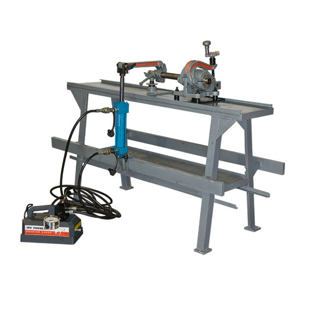 A metal pipe threading machine on a gray stand with an attached hydraulic power unit and control cables, used for cutting and threading pipes.