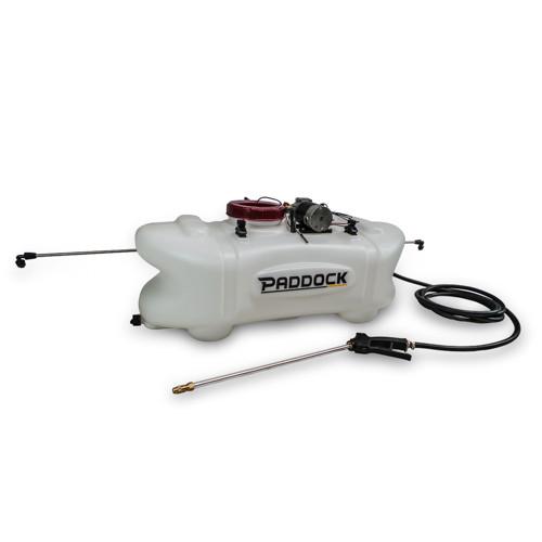 A white Paddock brand agricultural sprayer with a large tank, hose, spray wand, and mounted pump, designed for use with ATVs or vehicles.