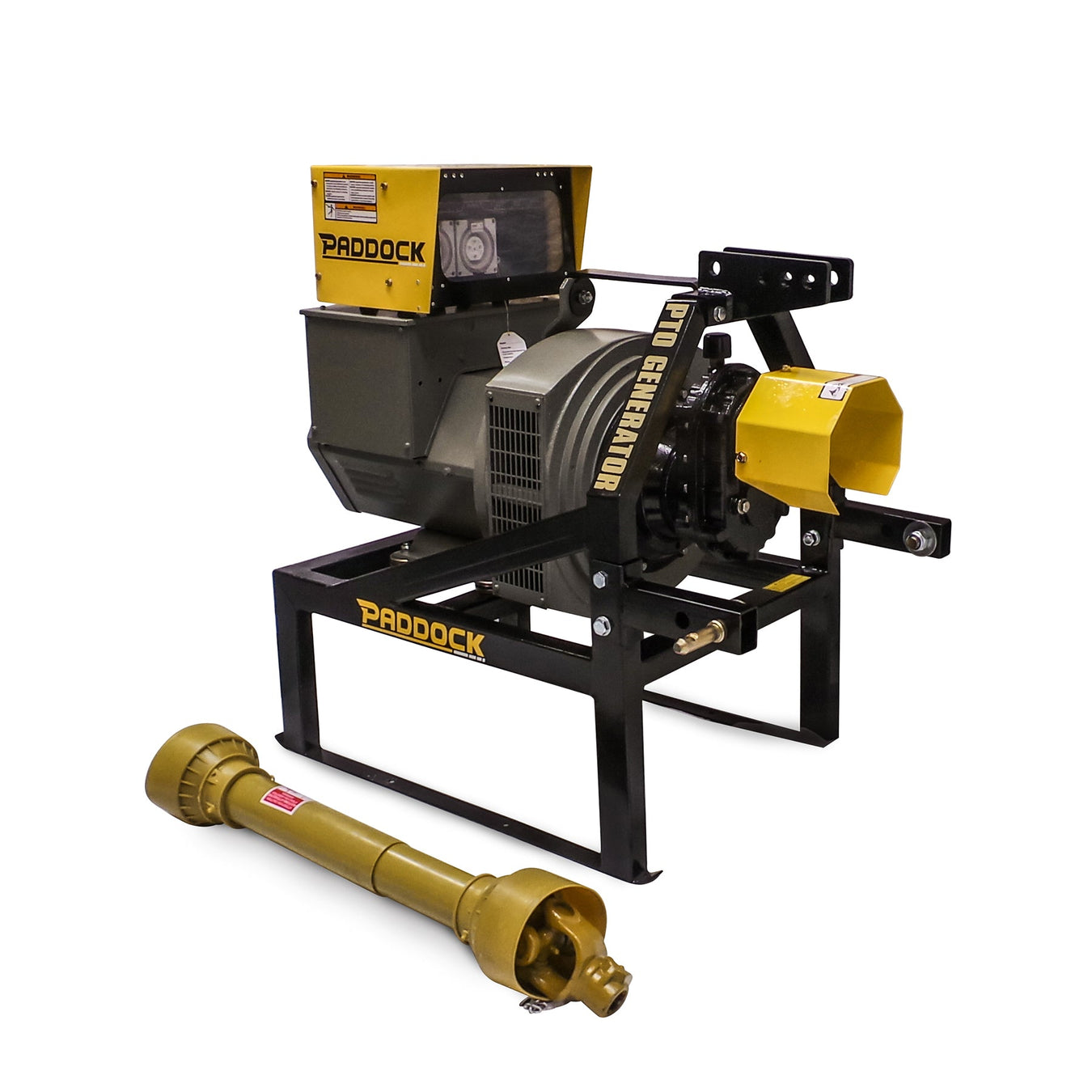 A PTO generator with a yellow and gray housing is mounted on a black metal frame labeled PRADDOCK. A yellow driveshaft attachment is placed in front of the generator.