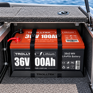 A red 36V 100Ah lithium battery secured by two black straps inside a Trolltek™ Aluminium Battery Tray Kit mounted in a boat compartment.