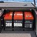 A red 36V 100Ah lithium battery secured by two black straps inside a Trolltek™ Aluminium Battery Tray Kit mounted in a boat compartment.
