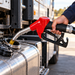 A hand holding a red Gravity Feed Automatic Diesel Nozzle – 8–50 L/min while dispensing fuel into the tank of a large truck.