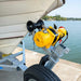 A Sherpa 4x4 Black Edition ‘Grunter’ Electric Boat Trailer Winch from Sherpa 4x4 is attached to a trailer, securely holding the front of a white boat parked near a calm lake with trees in the background. The bright, clear conditions suggest it is a sunny day.