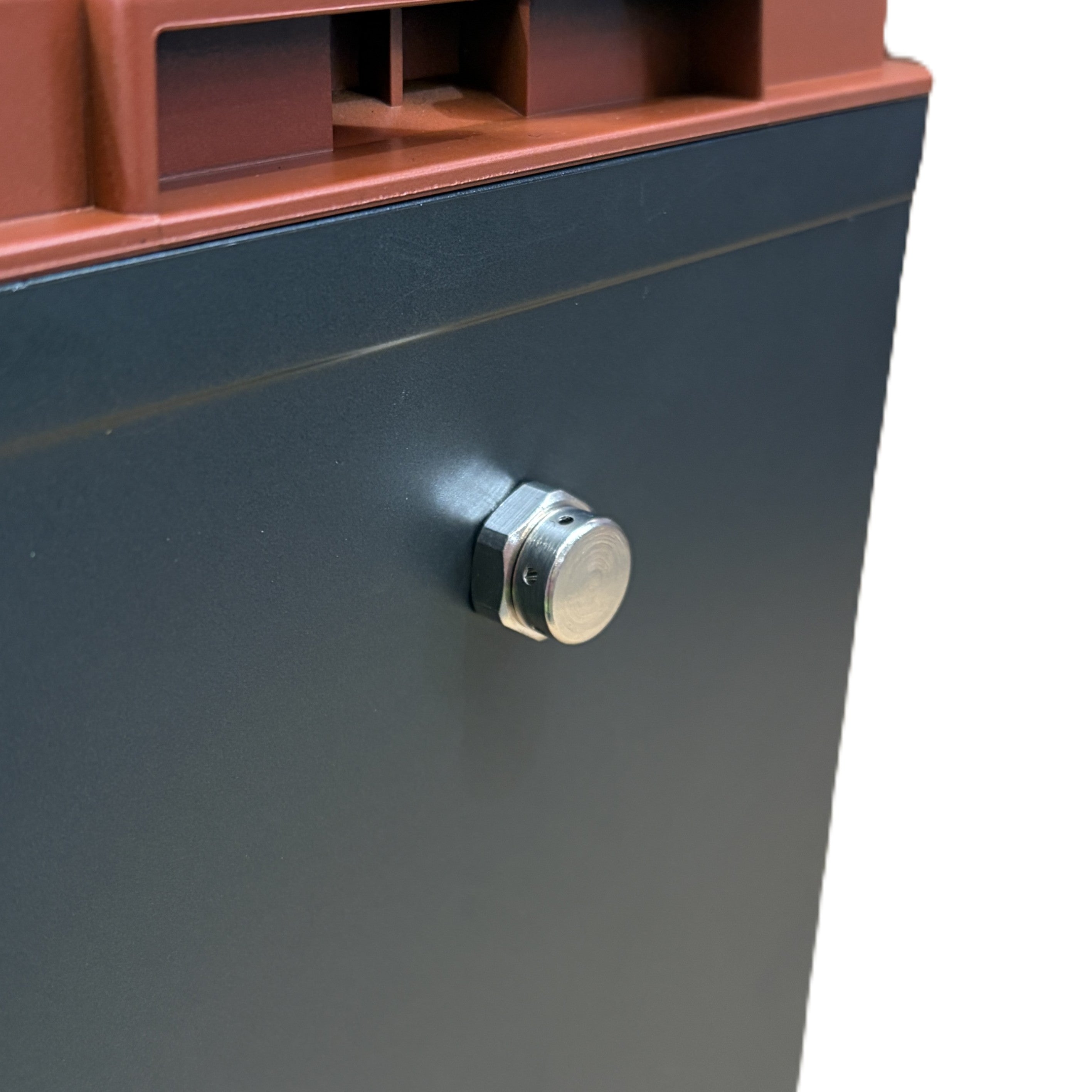 Close-up of a black and brown metal box featuring a round silver latch on its front panel. The smooth, slightly reflective surface resembles the robust housing of the Trolltek™ 12V LiFePO4 Lithium Battery 4WD Bundle – Charge While Driving (DC) from Trolltek.