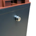Close-up of a black and brown metal box featuring a round silver latch on its front panel. The smooth, slightly reflective surface resembles the robust housing of the Trolltek™ 12V LiFePO4 Lithium Battery 4WD Bundle – Charge While Driving (DC) from Trolltek.