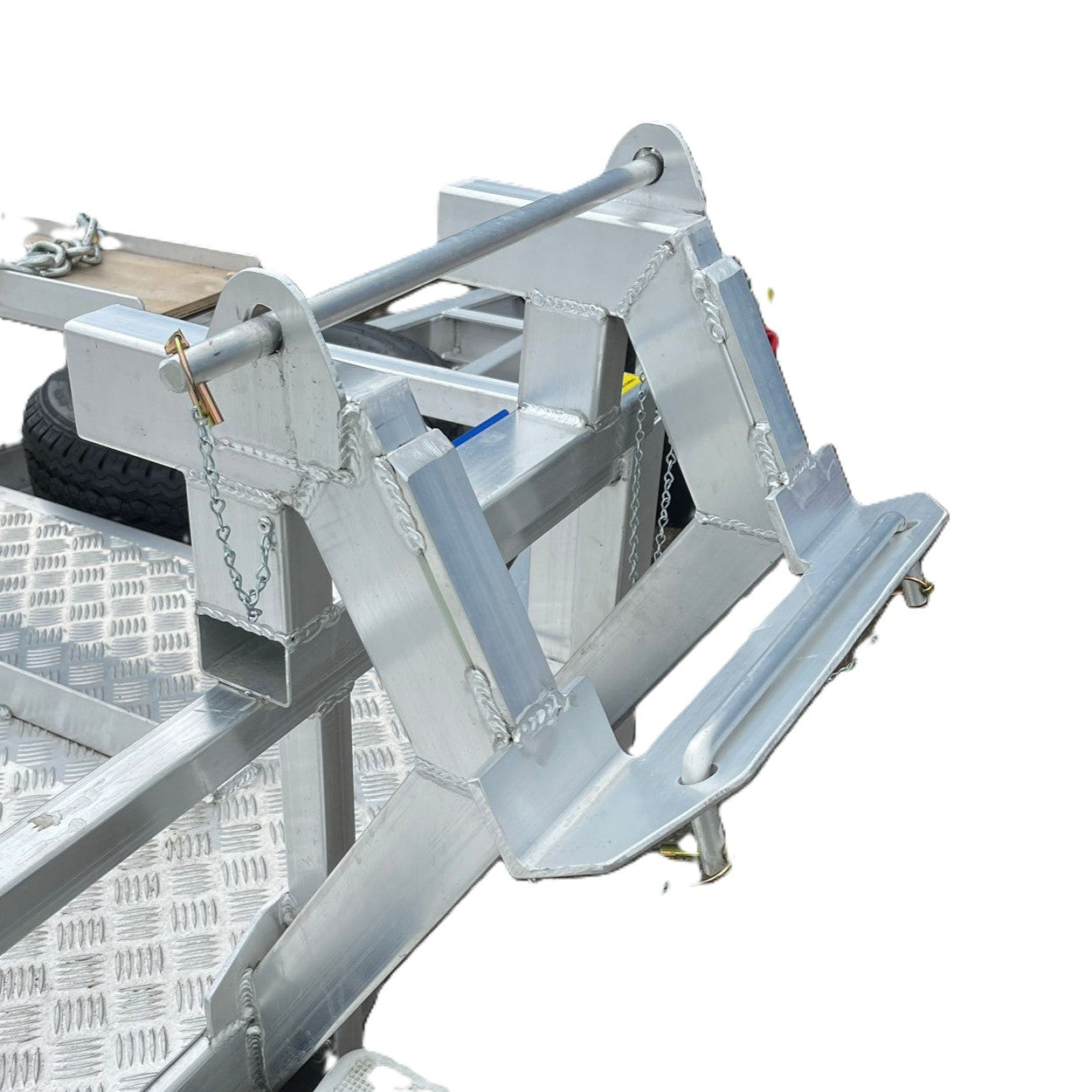 Close-up of a metallic trailer attachment with frame, bar, and lock on diamond plate surface. Ideal for securing or transporting heavy gear on Paddock Mini Loader & Excavator Alloy Equipment Trailers.