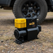 The Sherpa 4x4 'BIG AIR' Air Compressor (283 L/min) sits on the ground near an off-road vehicle’s wheel, ready for use.