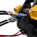 Close-up of black and red cables connected to a black and yellow mechanical device, likely a component of the Sherpa 4x4 ‘BIG V4’ Quad-Air Upgrade Kit – 4-Tyre Inflation System, featuring metal connectors and a blue fitting at the center. The out-of-focus background draws attention to the detailed parts of this Sherpa 4x4 upgrade kit.