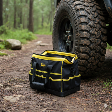 The Sherpa 4x4 Large Recovery Bag - Black & Yellow sits on a forest dirt trail beside a muddy Sherpa 4x4 tire, with trees and foliage in the background.