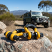 Two Sherpa 4x4 Recovery Shackle 4.7T (2pce set) rest on a rock, with a Sherpa 4x4 off-road recovery vehicle parked on a dirt track among trees and distant mountains under a clear blue sky.