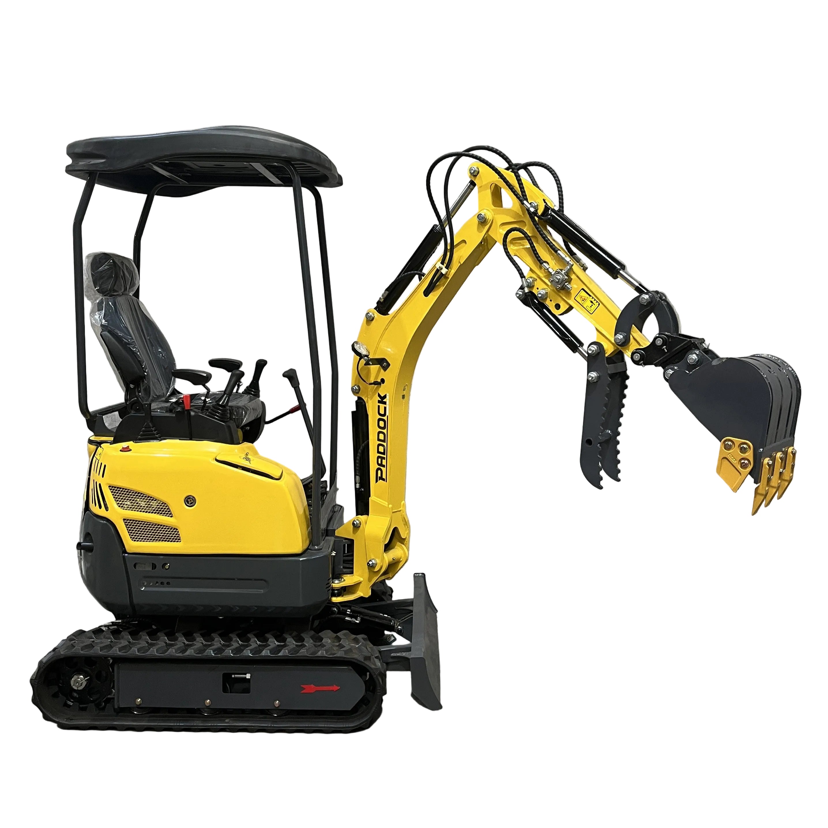 A compact yellow Paddock Excavator Series 17 with black cab and tracks is parked indoors against a concrete wall, its articulated arm and bucket—part of the 6 Attachments Bundle—extended forward.