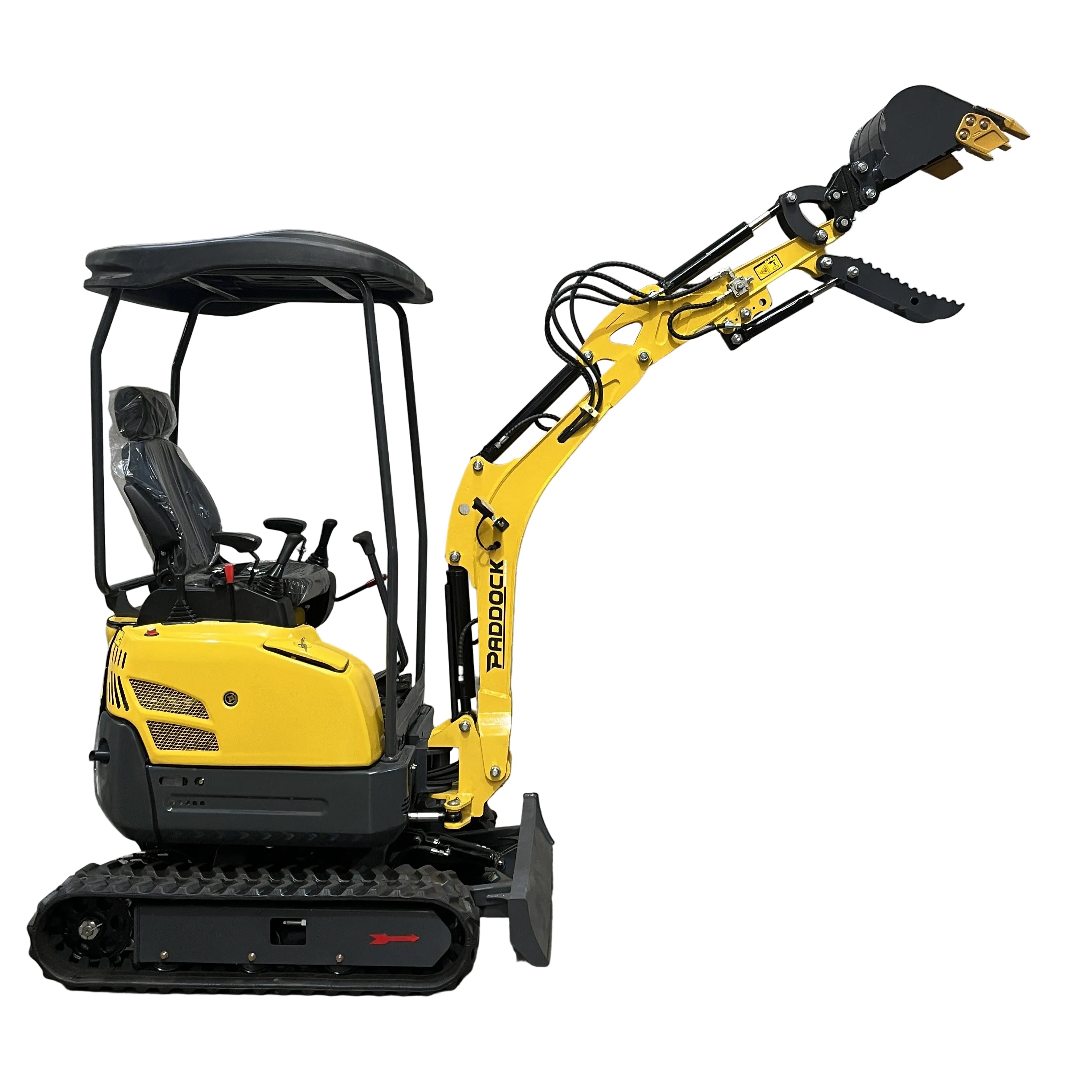 A Paddock Excavator Series 17 with a 6 Attachments Bundle sits indoors against a concrete wall. The yellow and black mini excavator features rubber tracks, a canopy, an articulated arm raised up, and its bucket slightly tilted.