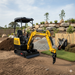 A compact yellow Paddock mini excavator fitted with a Paddock Excavator Ripper is parked on landscaped grounds near sod rolls, soil piles, garden tools, large rocks, and young trees.