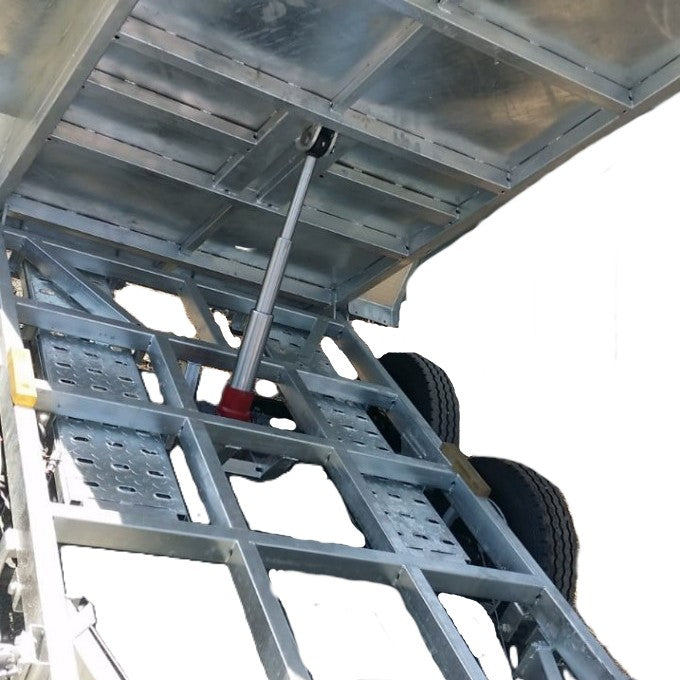 Close-up of the underside of a Paddock Mini Loader & Excavator Alloy Equipment Trailer being lifted by a hydraulic cylinder, showing two black wheels on the right side.