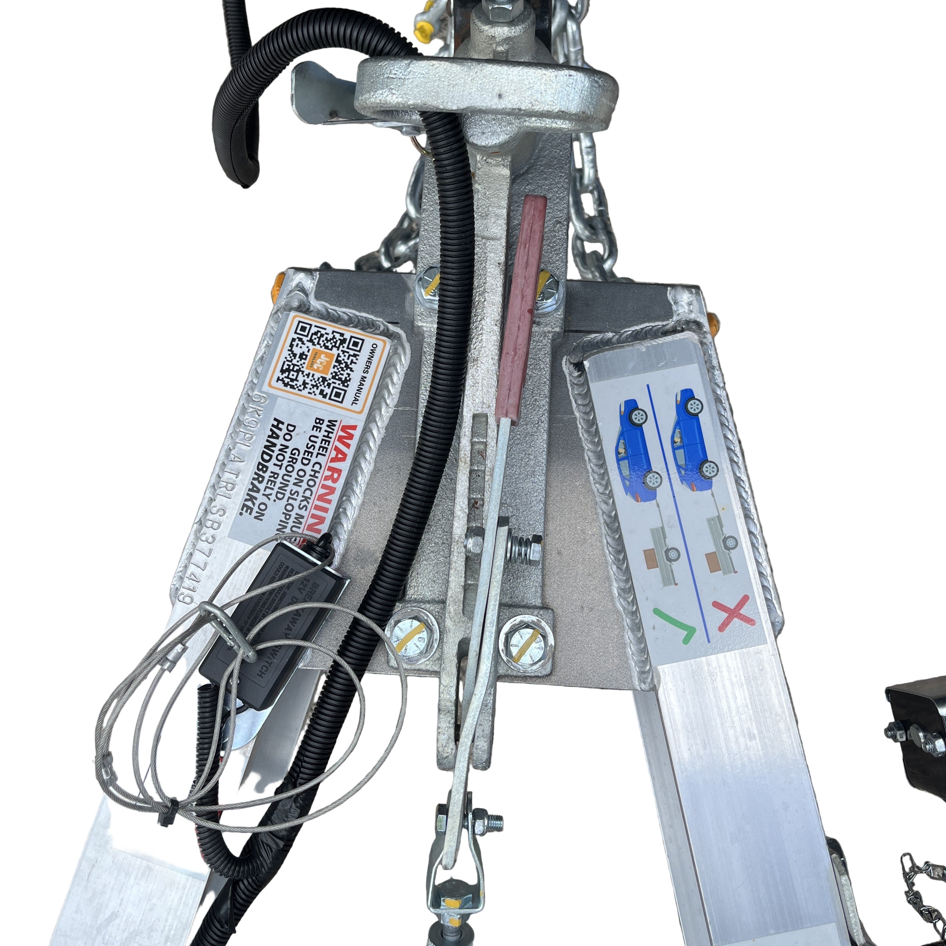 Close-up of the Paddock Mini Loader & Excavator Alloy Equipment Trailers’ metal mechanism by Paddock, displaying warning labels, a QR code, cables, and an instructional diagram with blue cars indicating correct and incorrect usage.