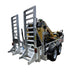 A Paddock Mini Loader & Excavator Alloy Equipment Trailer by Paddock, featuring dual ramps, transports yellow construction gear. Parked on concrete near an industrial building, it's built to handle tough jobs.
