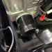 Close-up of a Paddock Loncin Oil Filter attached to a metallic engine block, with wires and cables on a glossy black surface—perfect for maintaining your RC Mower.