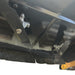 Close-up of the underside of a heavy machinery deck, showing two Paddock RC Mower Finishing Blade Set blades by Paddock mounted with bolts, assorted metal parts, and part of a protective rubber skirt along the edge.