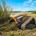 The Paddock™ Remote Controlled Mower 16HP - 740mm by Paddock, equipped with tank-like treads, expertly handles slope mowing and cuts tall grass in a rural field beneath a blue sky with scattered clouds.