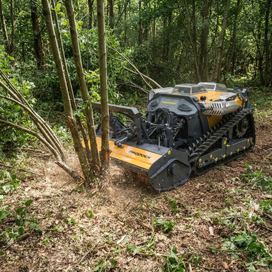 The Paddock™ Remote Controlled Mower/Slasher/Mulcher 35HP - 1150mm by Paddock mulches small trees and brush on a forest floor, surrounded by greenery and scattered branches.