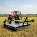 A red tractor with a Paddock 4.6ft Tractor PTO Slasher is parked in a field, its galvanised steel frame gleaming amid grass and farmland under a partly cloudy sky.