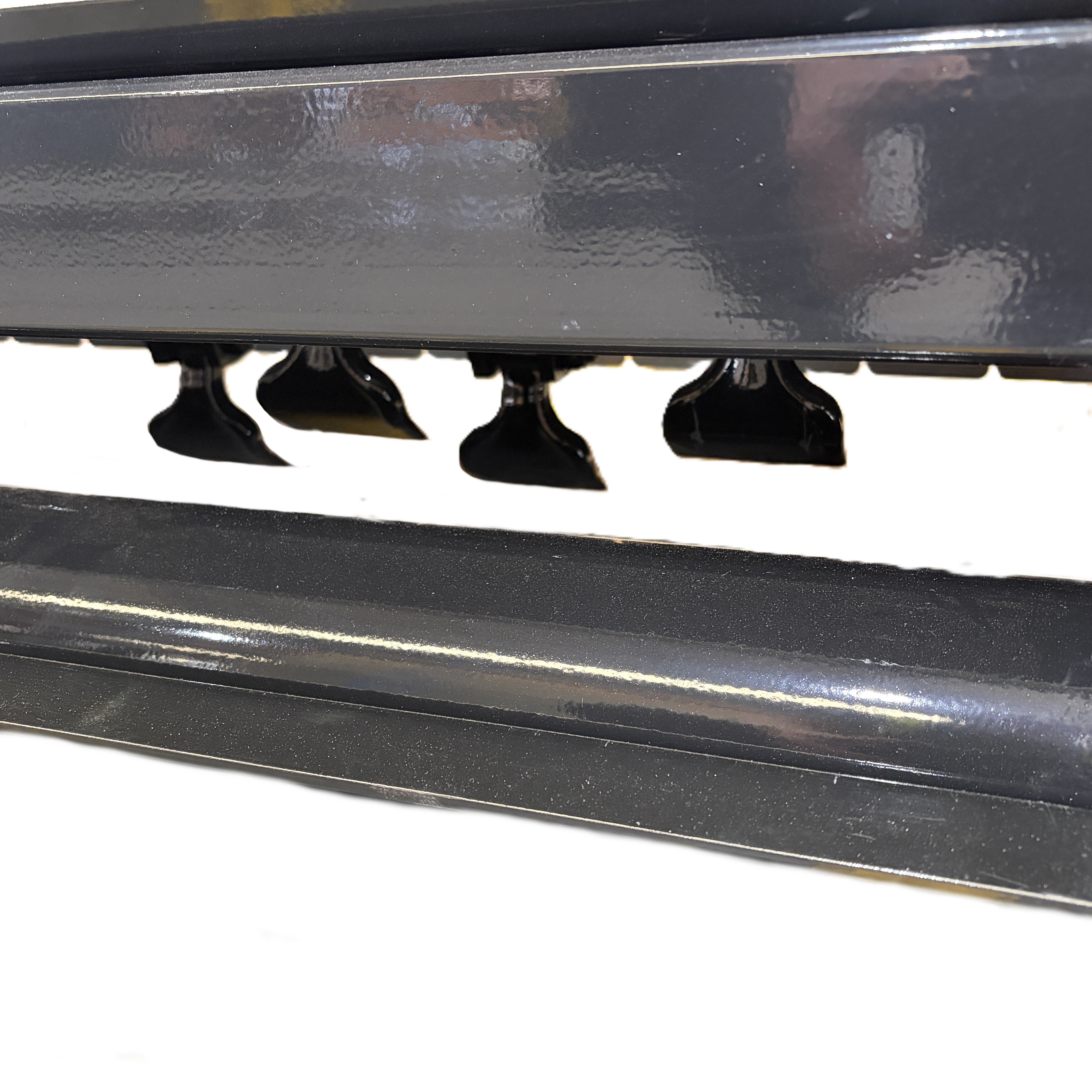 Close-up of the Paddock™ PTO Offset Verge Flail Mower by Paddock, showing its row of flat, paddle-like black blades suspended from a dark metal frame, designed for heavy-duty mowing applications, set against a white background.