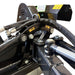 Close-up of metal components and fittings—including bolts, hydraulic hoses, and warning labels—on the Paddock™ PTO Offset Verge Flail Mower by Paddock. The parts are finished in black with yellow highlights, set against a white background.