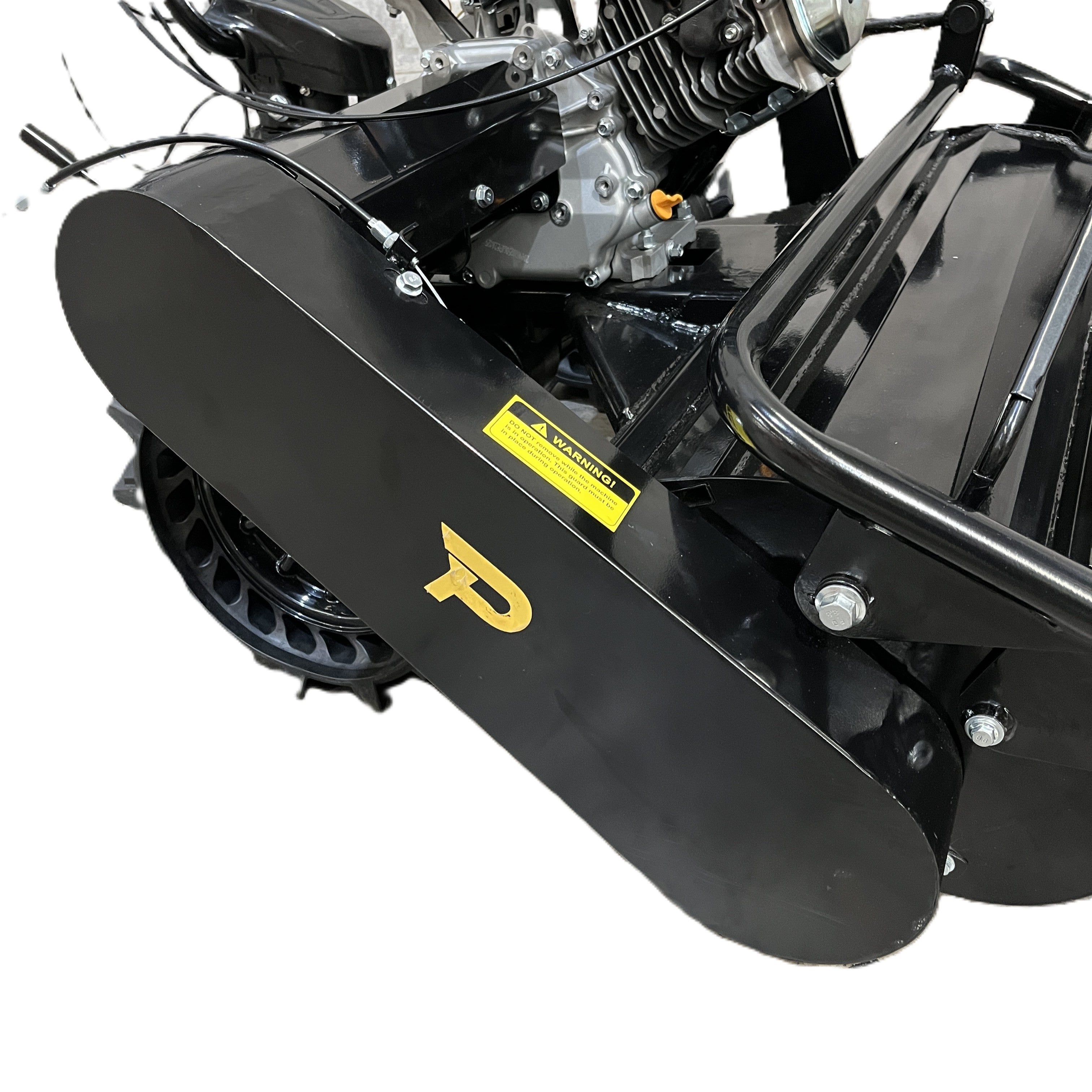 Close-up of the Paddock Walk Behind Flail Mower 12HP - 900mm in black, featuring a visible engine and yellow P logo. This heavy-duty mower, ideal for vegetation control, sits on concrete with a yellow warning label above its metal cover.