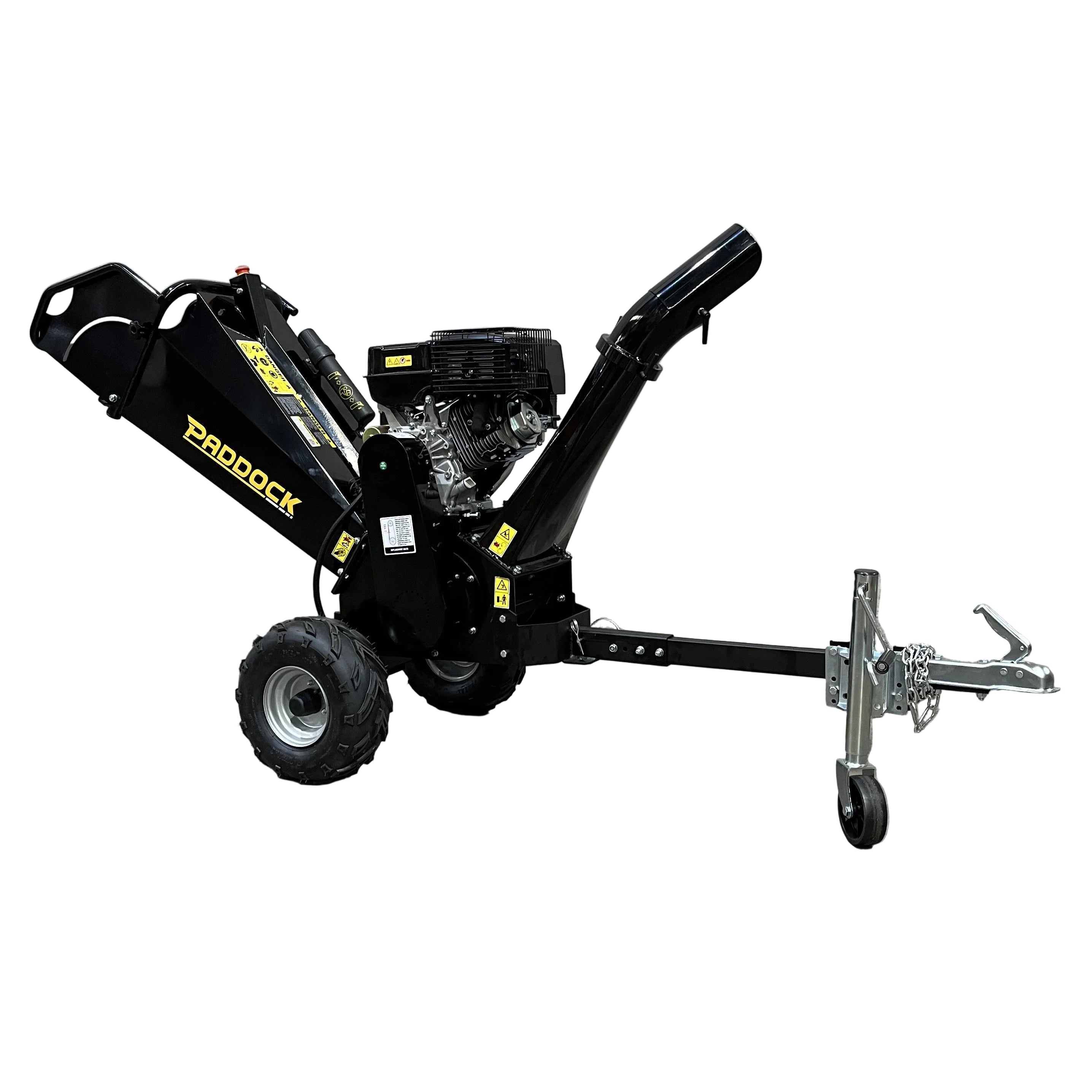 A Paddock Wood Chipper Mulcher by Paddock with large wheels and a tow hitch stands on a concrete floor before a gray textured wall, featuring a chute for wood debris and visible petrol engine parts.