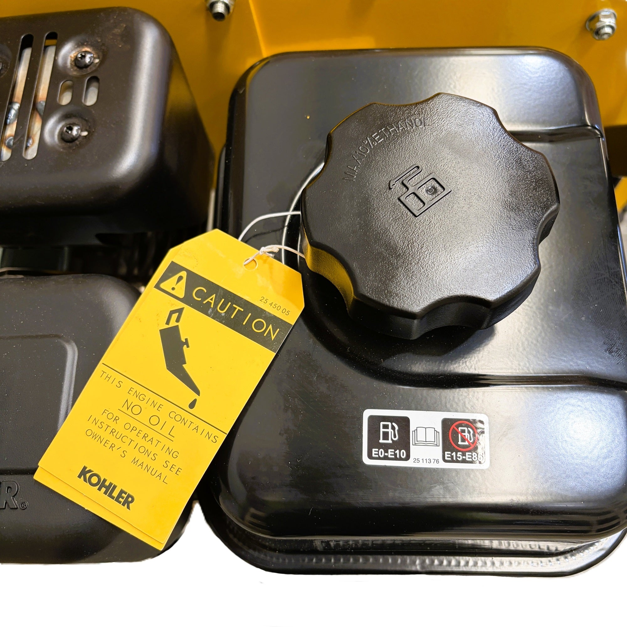 Black fuel tank on the Paddock™ Wood Chipper Shredder 75mm’s 6.5hp Kohler engine, featuring a circular cap and a yellow caution tag indicating that the engine contains no oil.