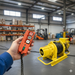 Someone uses the Sherpa 4x4 240/415V Winch Wireless Kit to operate a yellow industrial winch in a spacious warehouse filled with shelves, boxes, and forklifts.