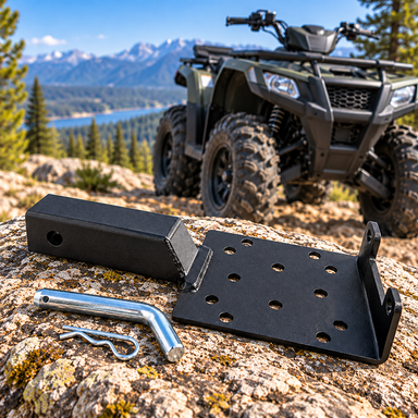 A heavy-duty steel Sherpa 4x4 ATV Winch Hitch Mount with a hitch pin and clip resting on a rock in front of an ATV.
