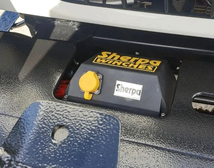 A close-up of a Sherpa 4x4 Black Edition ‘Stallion’ 25,000Lb Winch, featuring yellow and white Sherpa 4x4 branding, mounted on a textured metal surface.