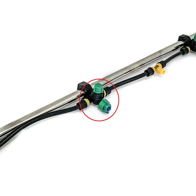 Close-up of a metal pipe with black tubing and plastic connectors; a green and blue Scintex Paddock Spray Boom Tee Fitting Assembly is highlighted in red, showing its use for efficient spray distribution on Paddock sprayers.