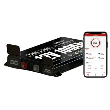 A black 12V Trolltek™ LiFePO4 Super Slimline Lithium Battery with Bluetooth app, featuring a display panel and terminals, is shown next to a smartphone displaying the battery monitoring app screen from Trolltek. This highlights its advanced battery management system from Trolltek for enhanced performance and long cycle life.